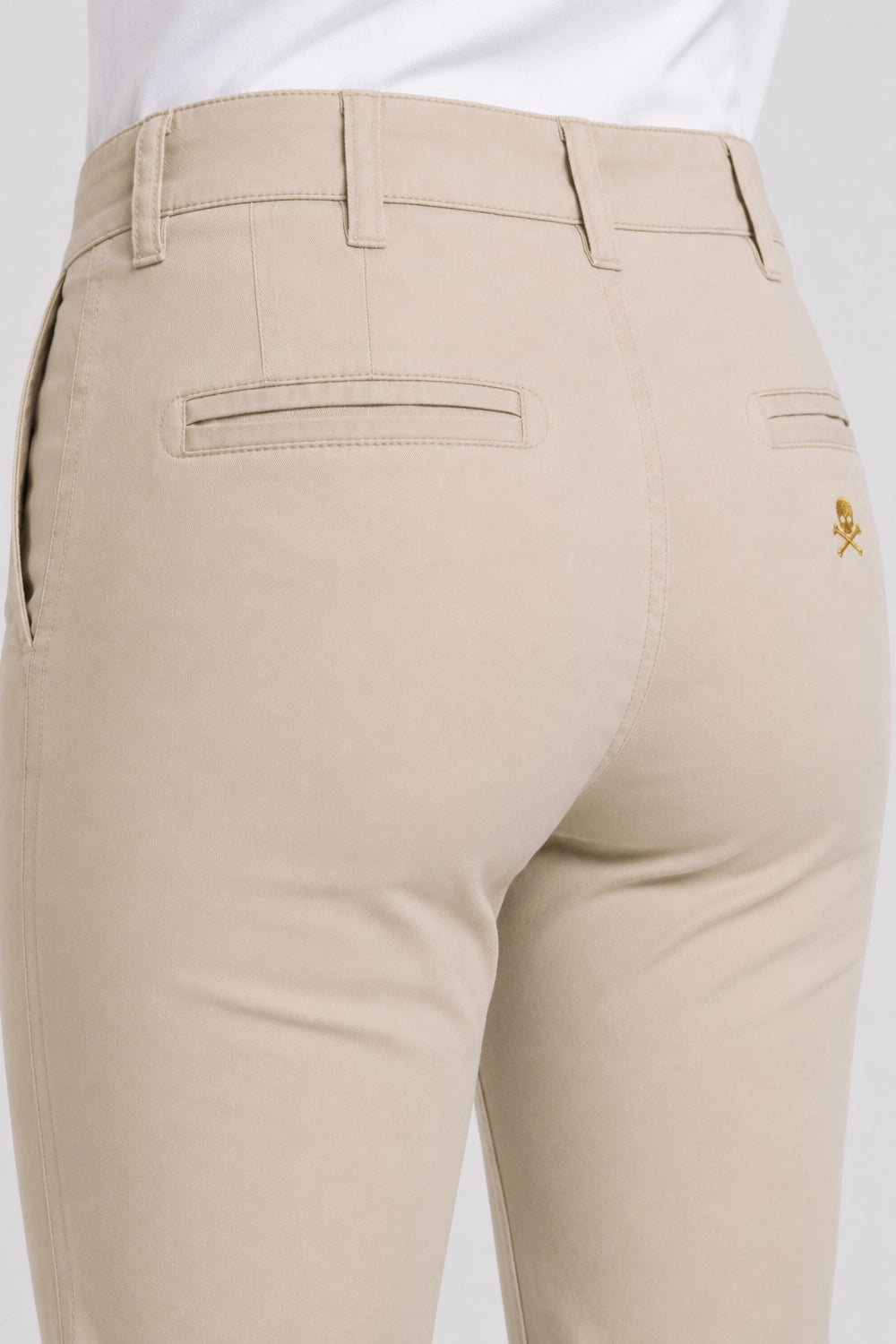Pantalon chino de golf beige clair, gros plan sur la poche arrière et couture décorative.