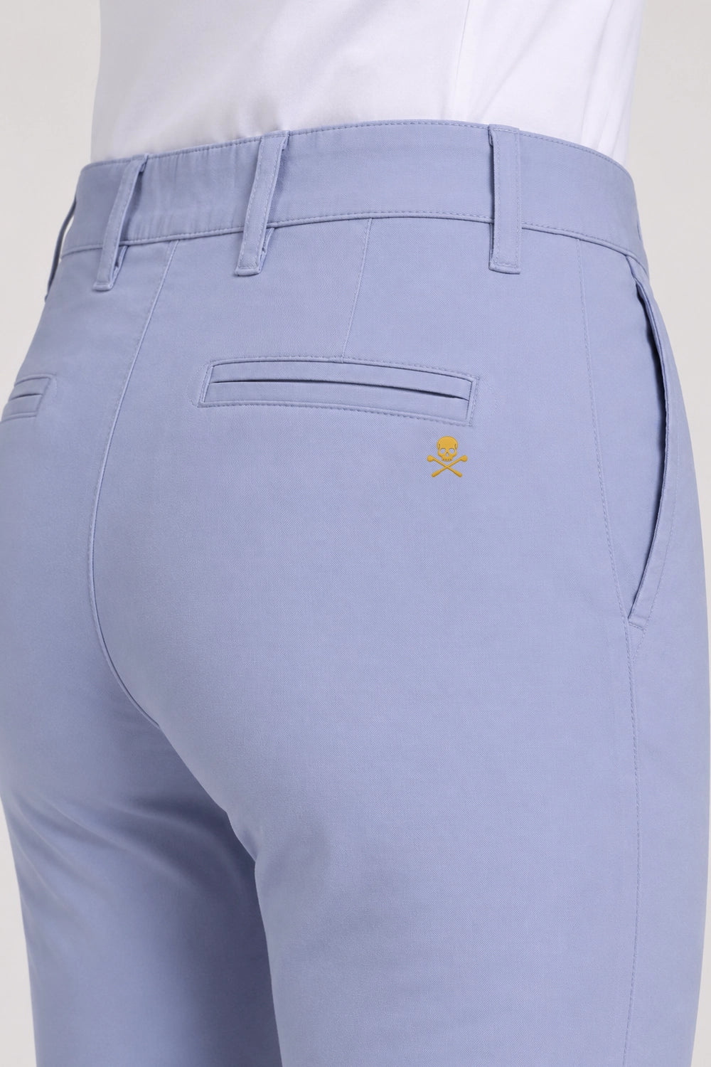 Pantalon de golf chino bleu clair, poche arrière et emblème discret.