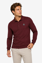 Polo manches longues en coton bordeaux, vue trois-quarts, patte de boutons et écusson.