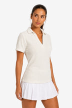 Polo femme beige clair, col V, coupe cintrée, manches courtes.