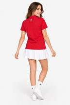Polo fille coton rouge, col et patte boutonnée, petit logo dos; jupe blanche plissée