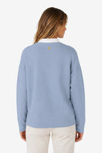 Sweat-shirt de golf pour femme ample bleu ciel, vue dos avec petit logo sur le haut.