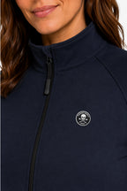 Veste de golf déperlante bleu marine, badge poitrine rond et zip noir visible.