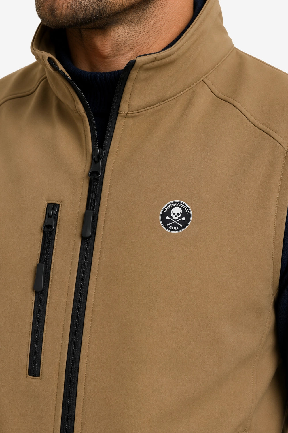 Veste golf sans manches déperlante beige, détail zip noir et écusson sur la poitrine.