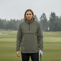 Femme portant une veste de golf imperméable kaki sur un terrain de golf sous la pluie.