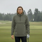 Femme portant une veste de golf imperméable kaki sur un terrain de golf sous la pluie.